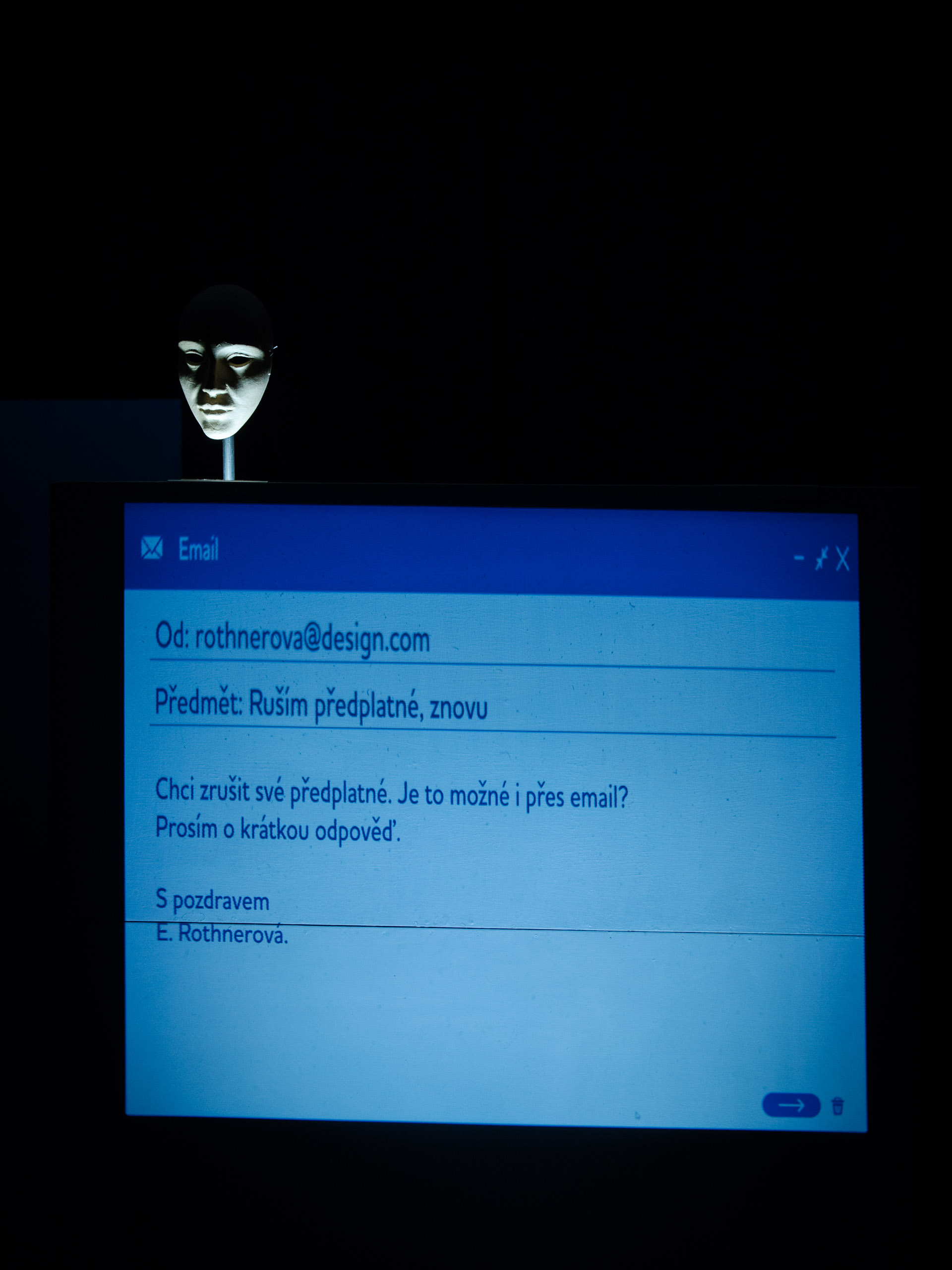 A mask looms over a computer screen displaying an email requesti