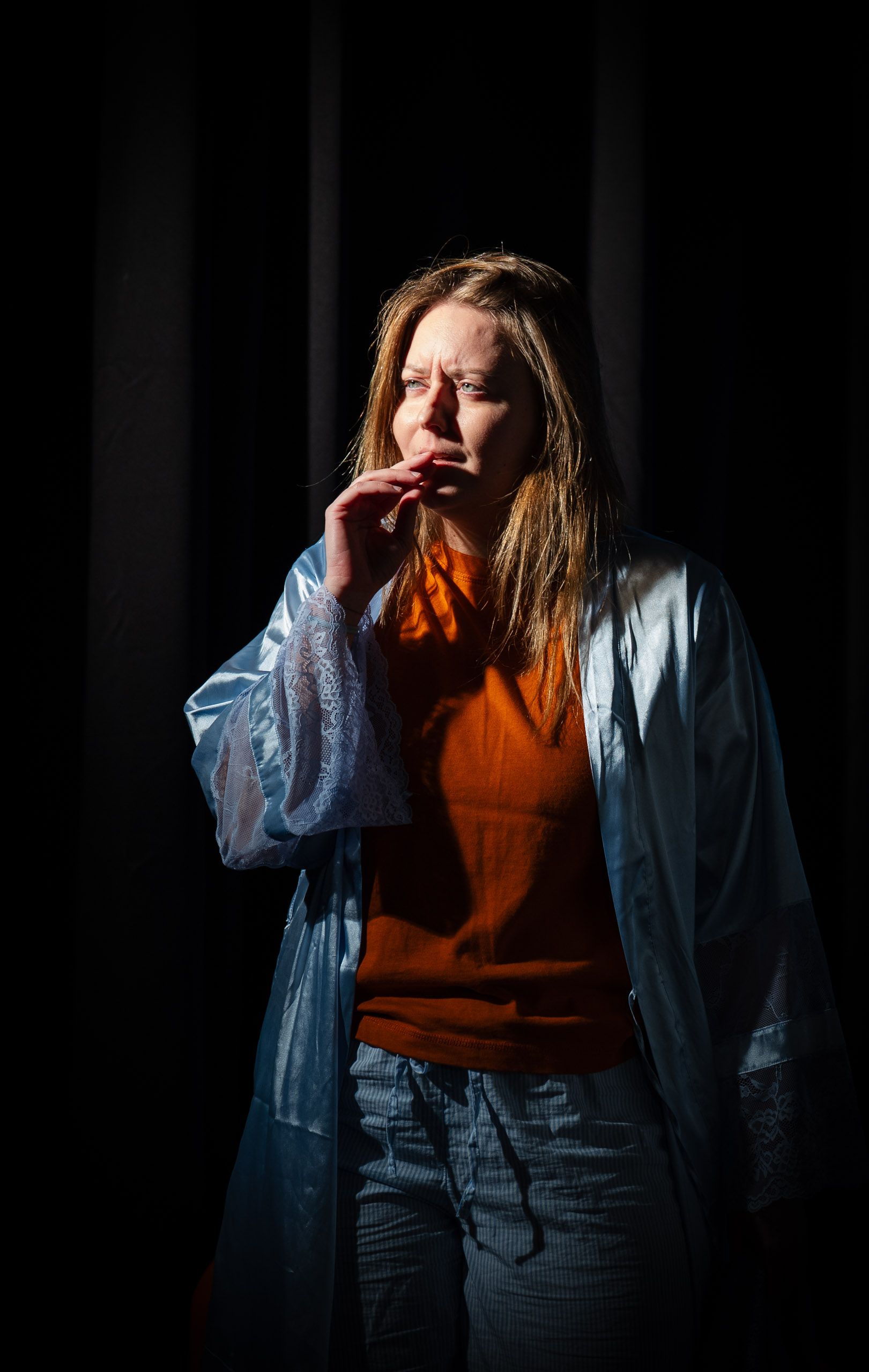A woman in pajamas and a robe looks thoughtfully into the distan