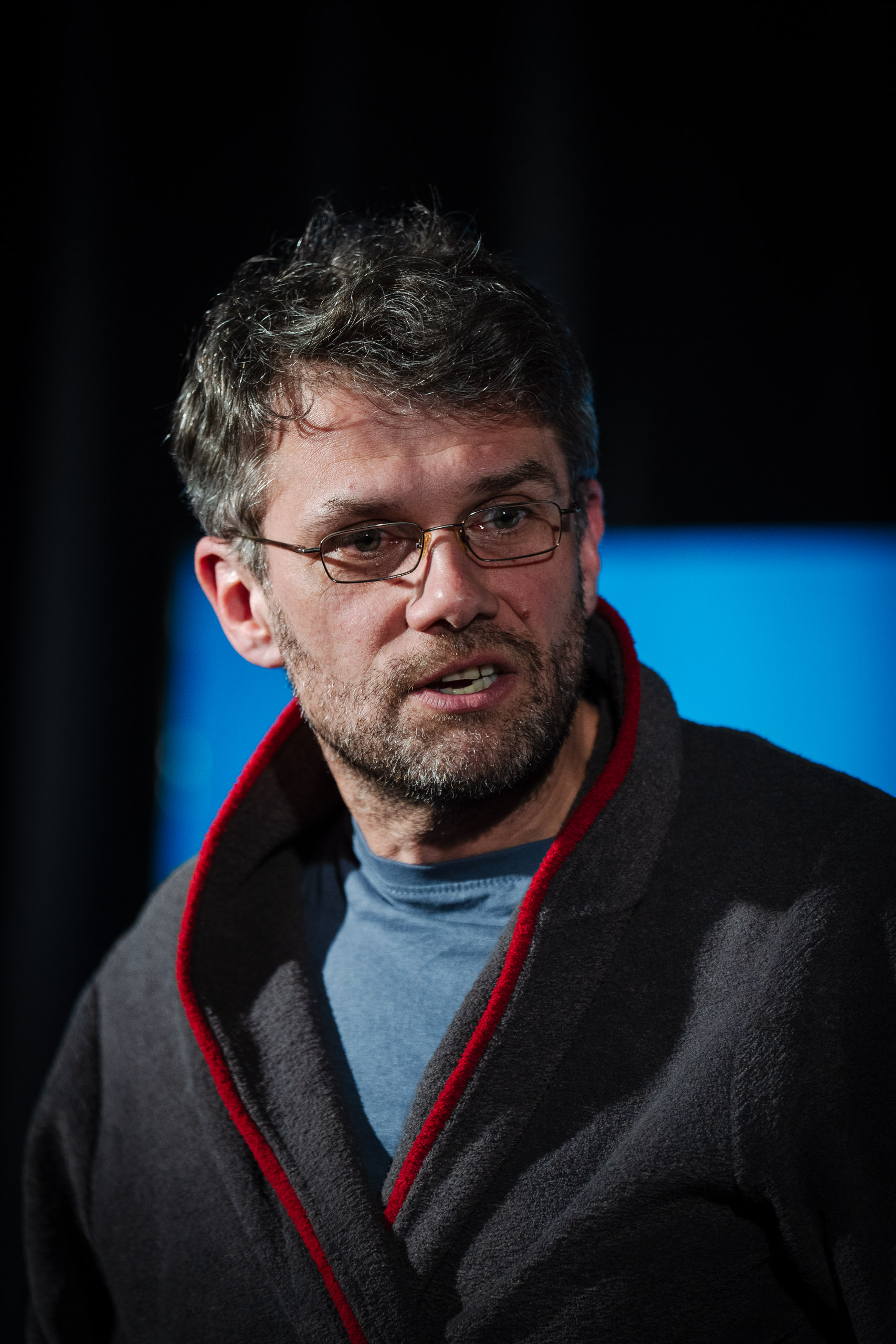 A man with glasses and a beard speaks.
