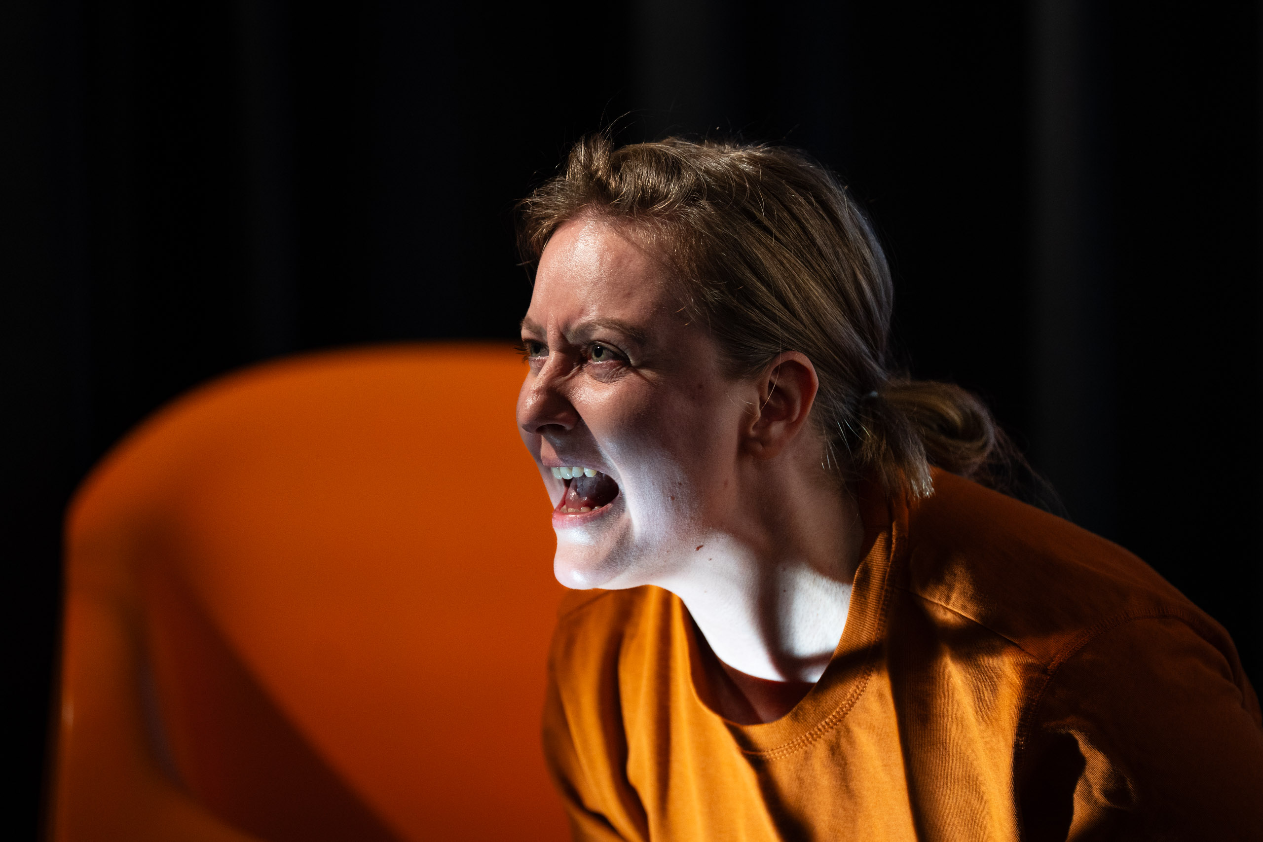 A woman with blonde hair pulled back in a ponytail, wearing an o