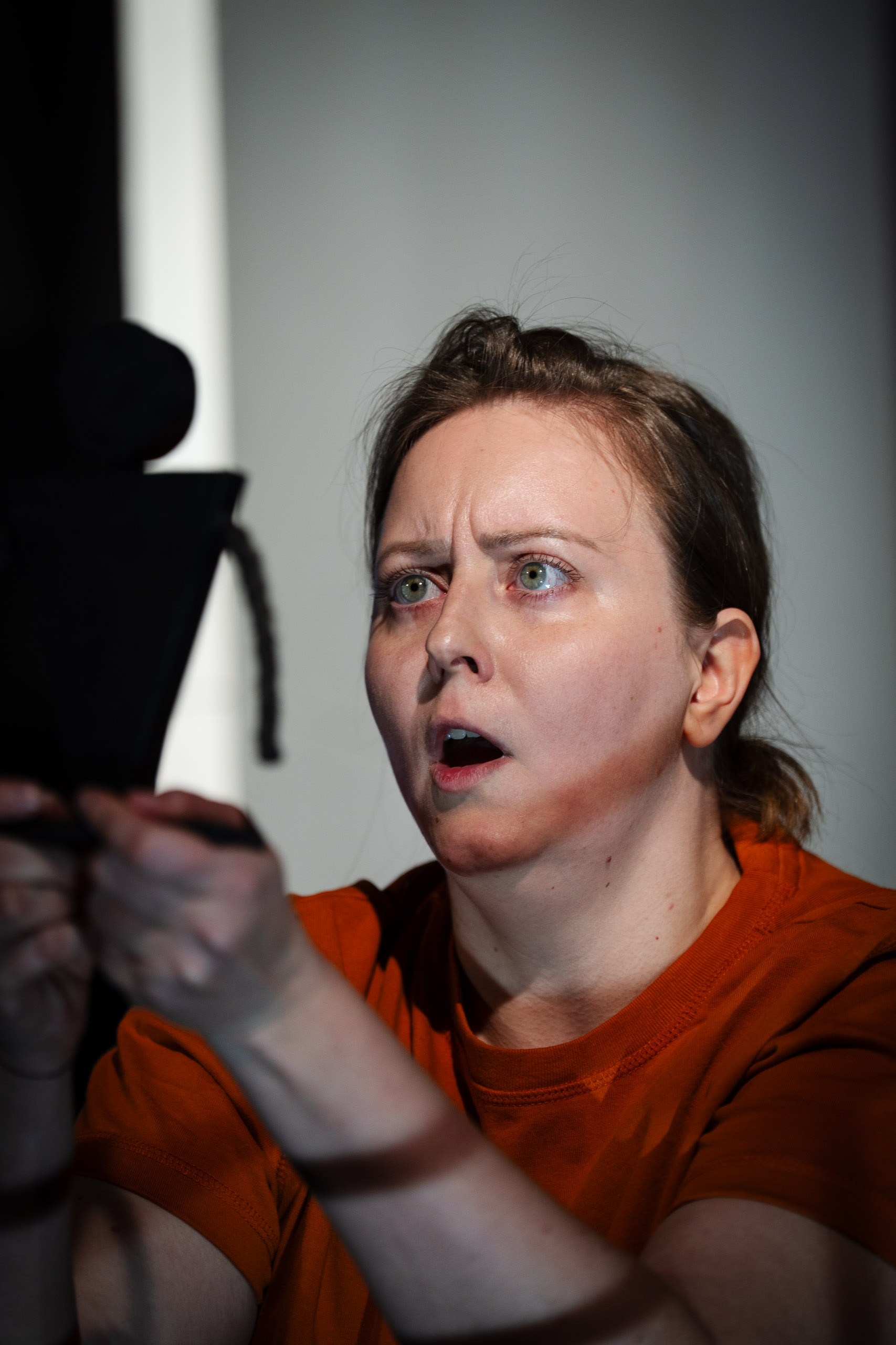 A woman with an astonished expression looks at a black cutout fi