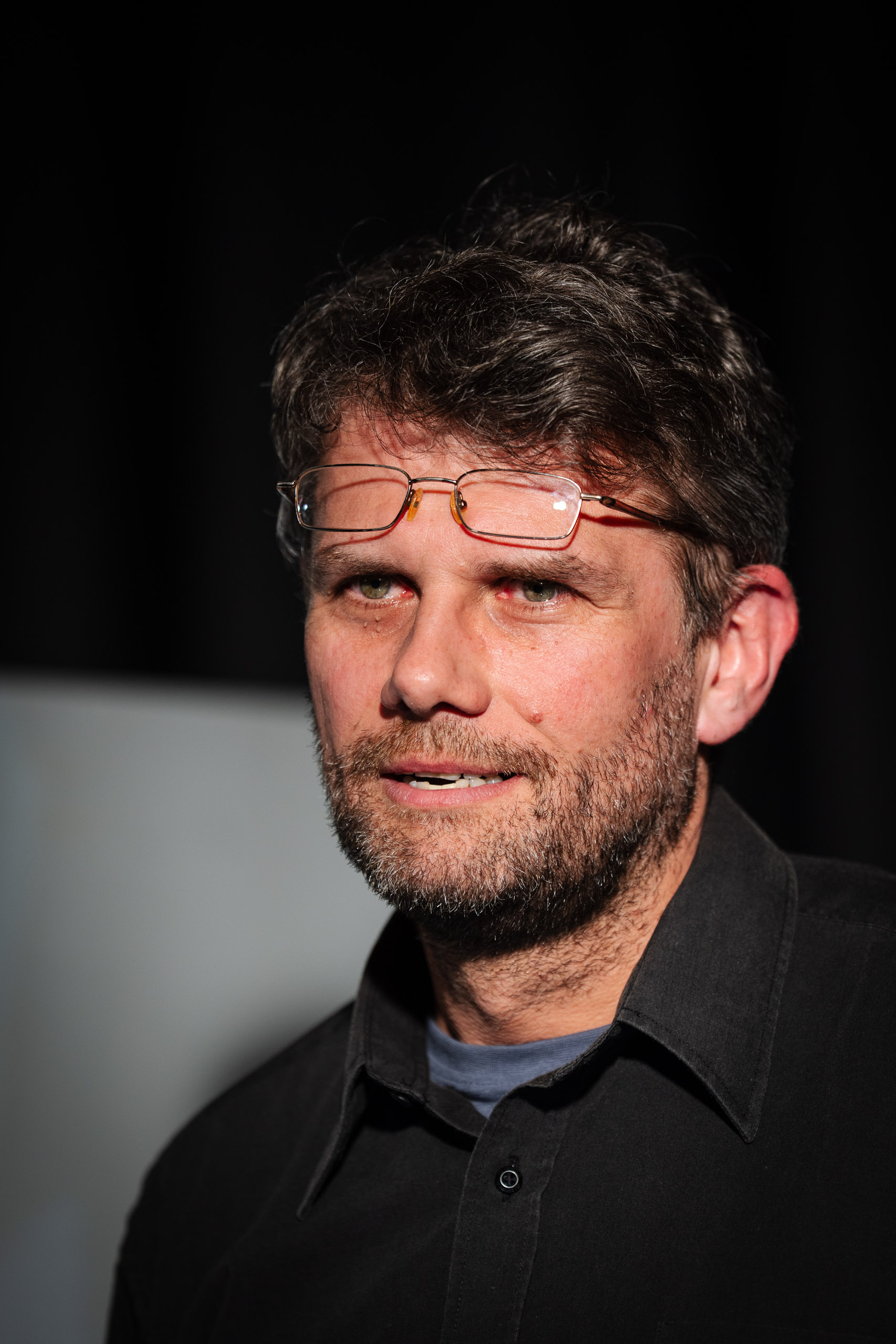 A man with glasses and a beard looks to the side.