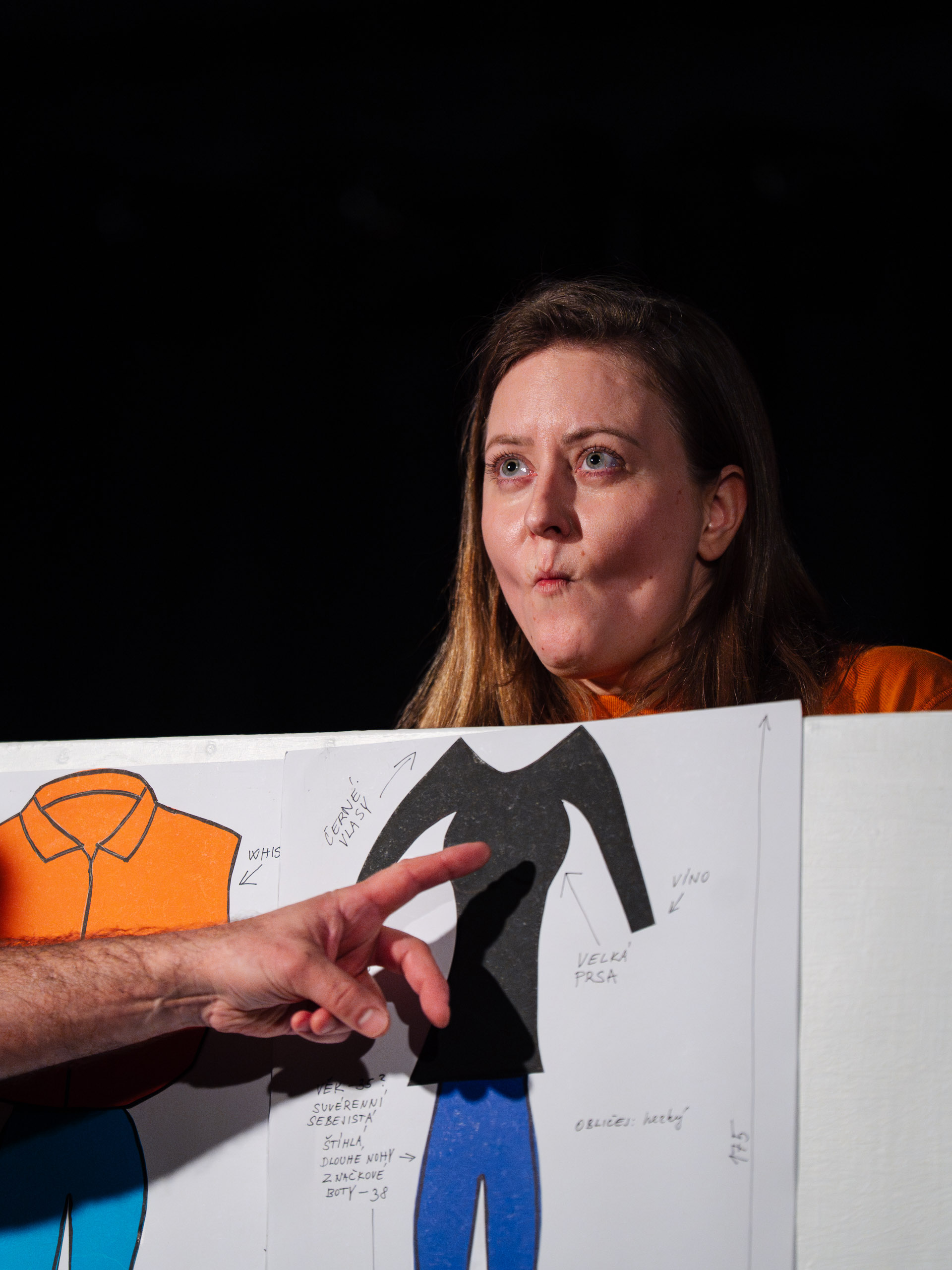 A woman looks at a drawing of clothing with annotations.
