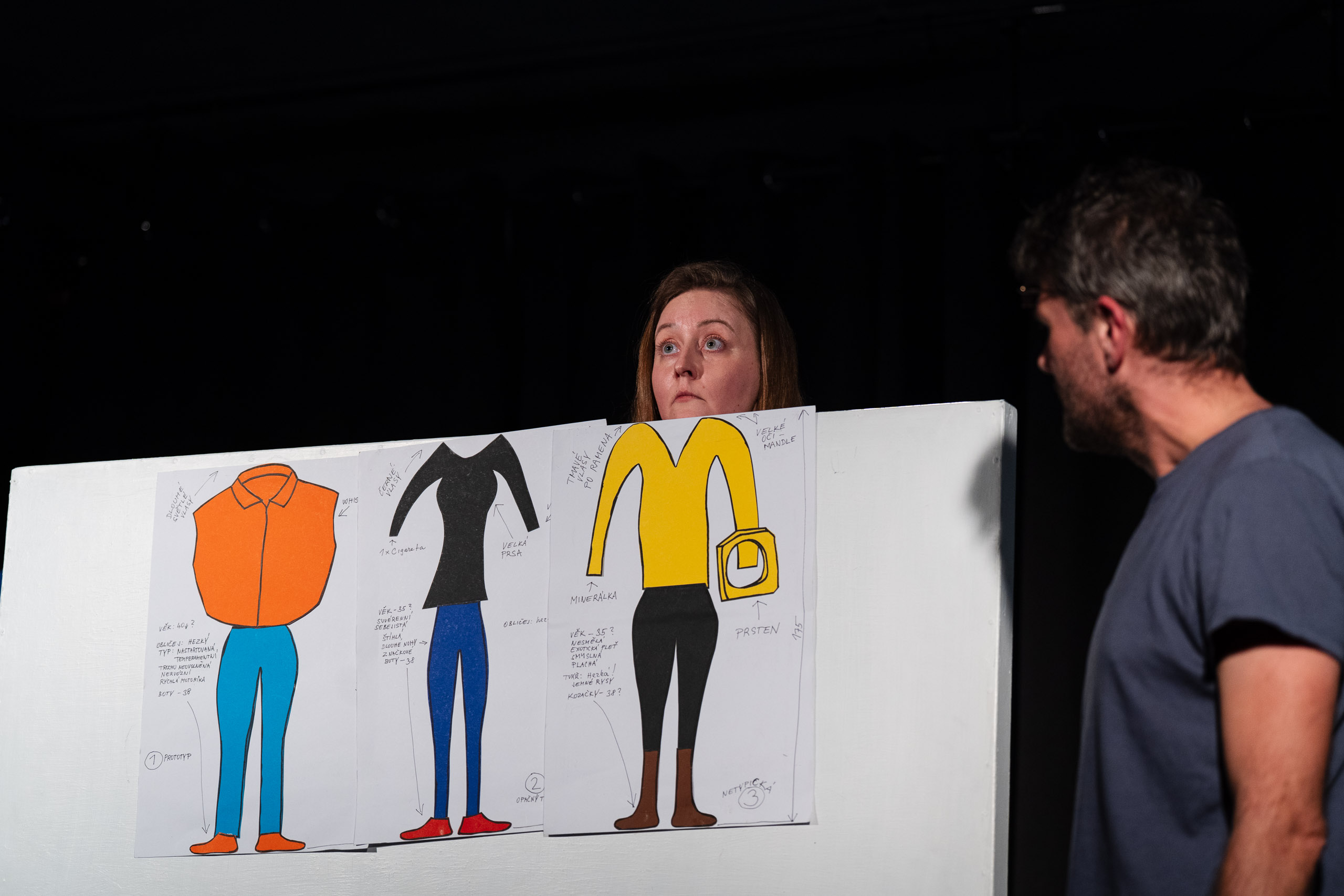 A woman looks at drawings of characters while a man watches.