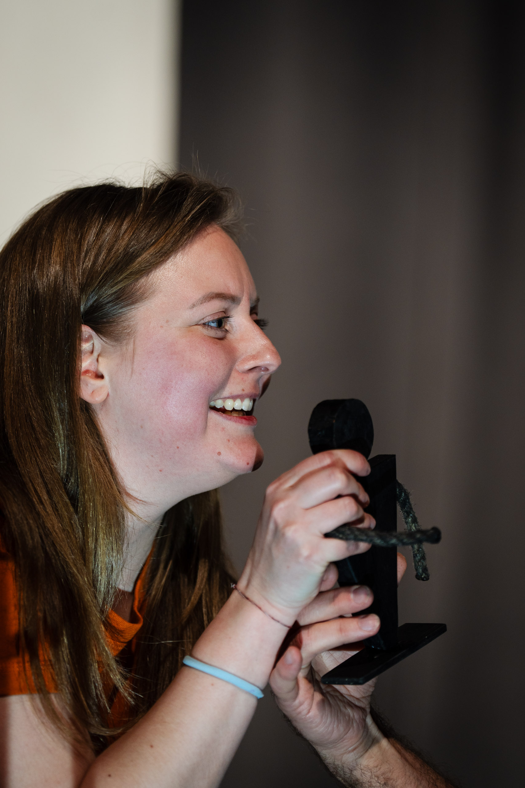A woman laughs while holding a small black figure with a rope.