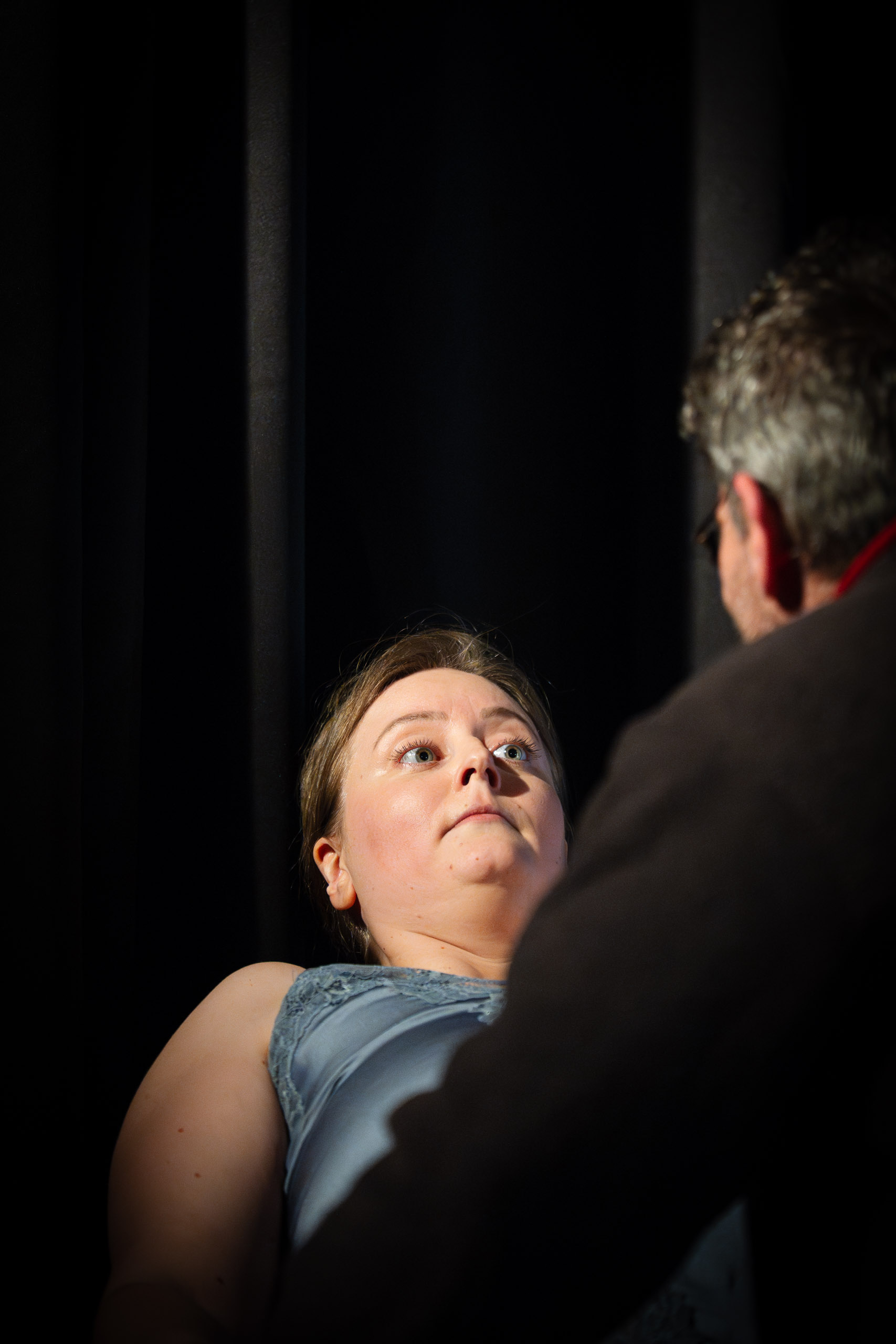 A woman looks up in surprise as a man looms over her in a dramat