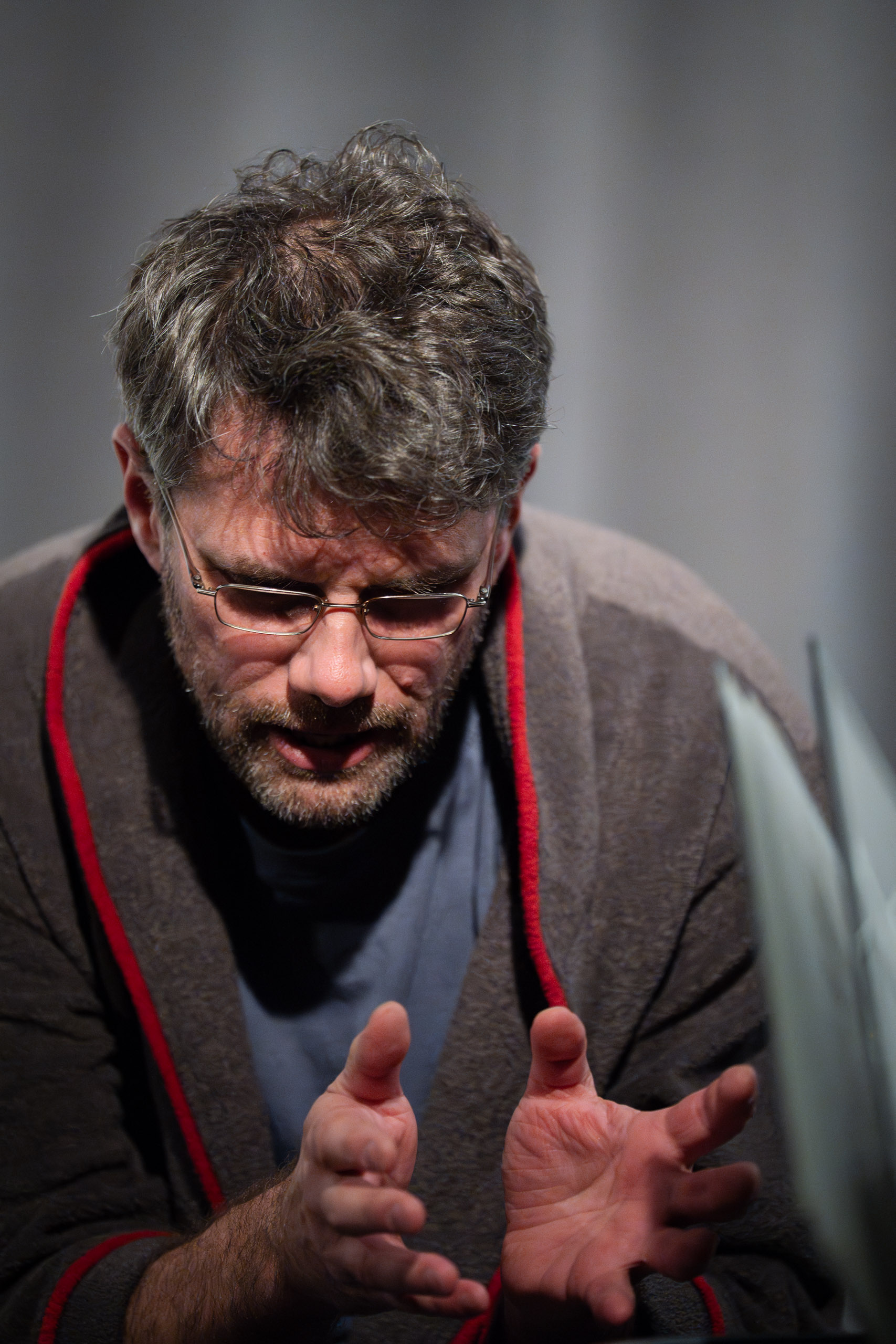 A man with glasses and a beard gestures with his hands while spe