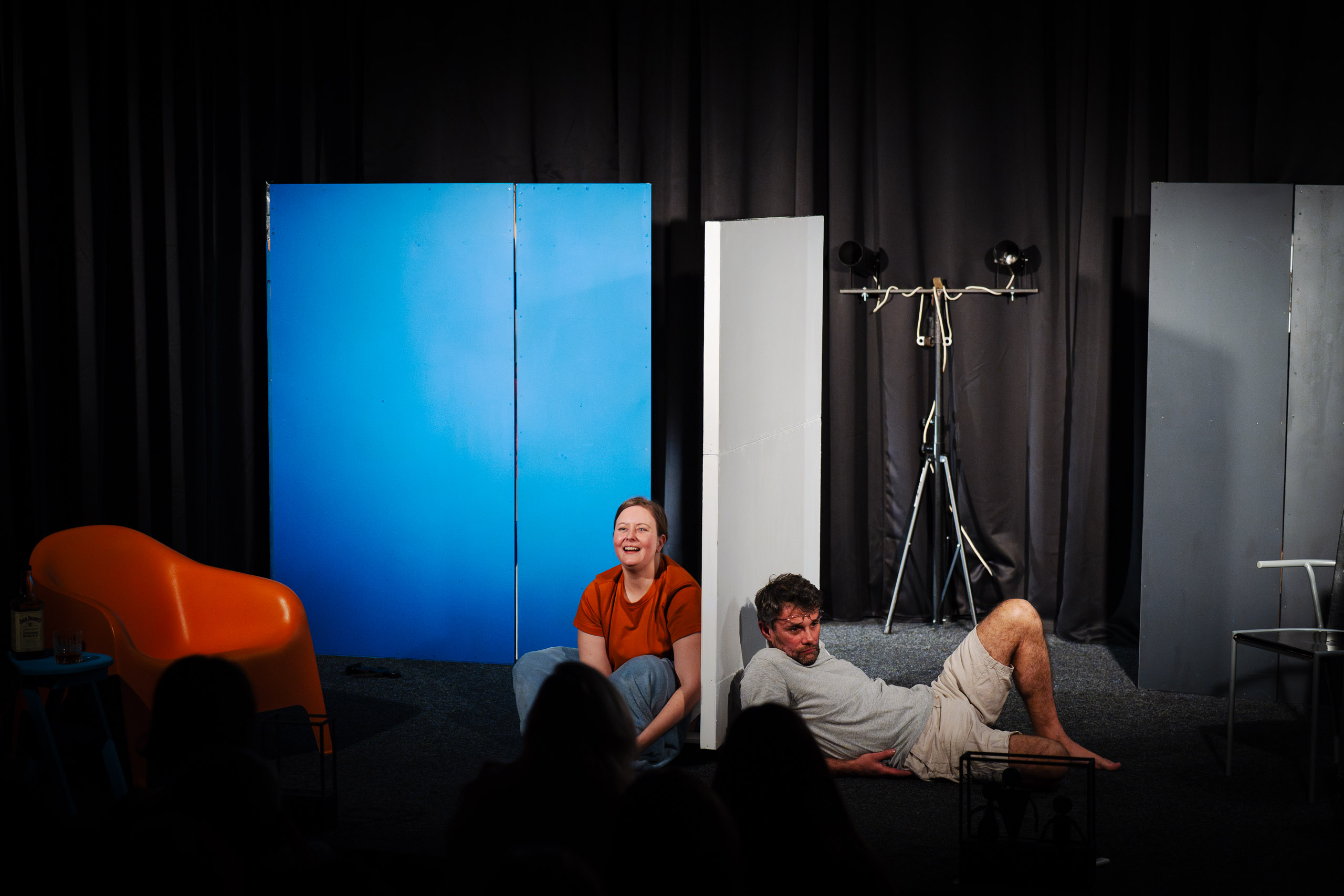 A woman and a man on stage during a performance, with abstract s