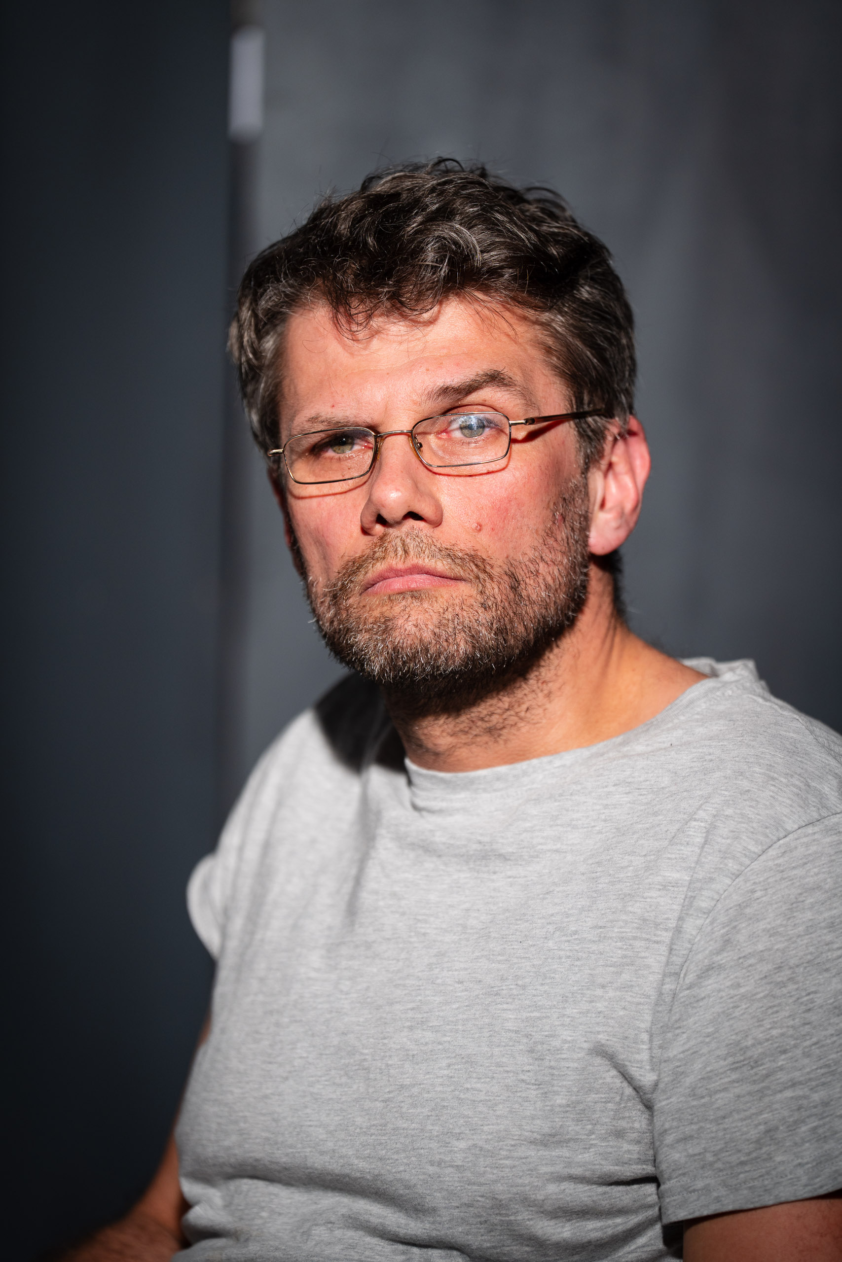 A man with glasses and a beard looks directly at the camera.