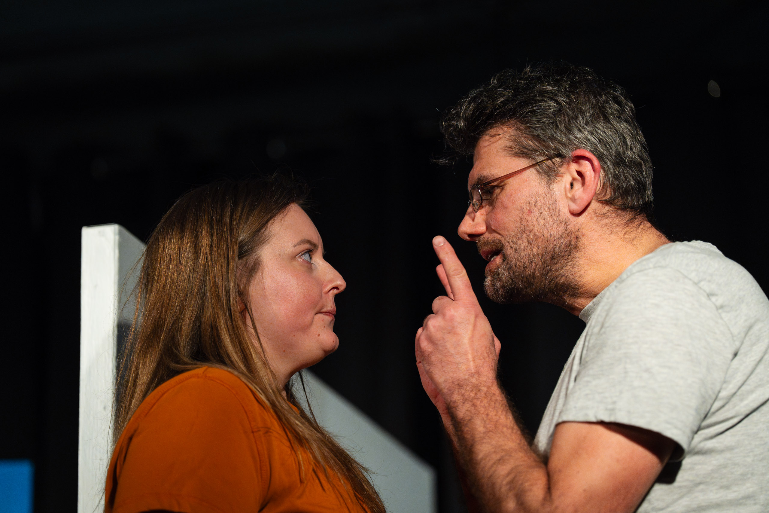 A man gestures emphatically at a woman during a tense confrontat