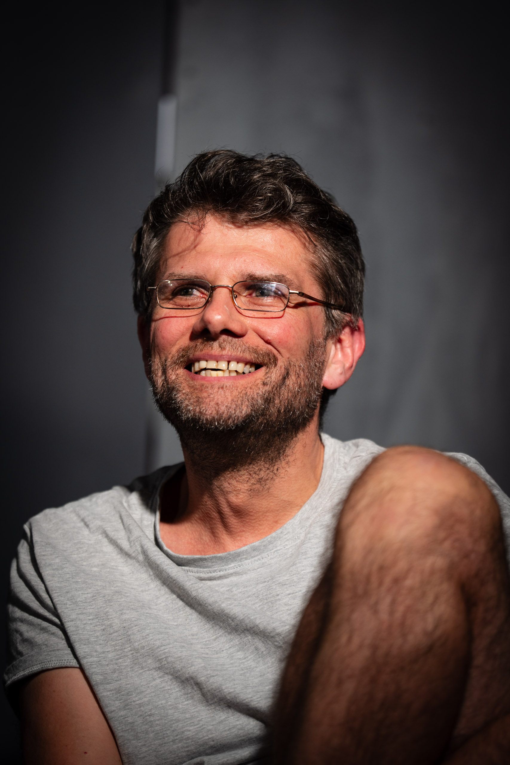 A man with glasses and a beard smiles.